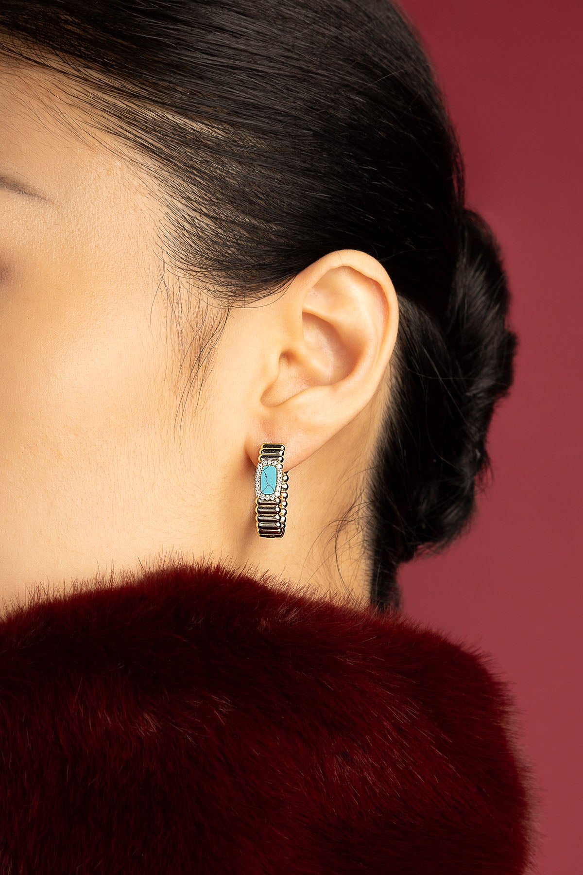 Woman wearing APM Monaco hoop earrings, a turquoise touch of quiet elegance.