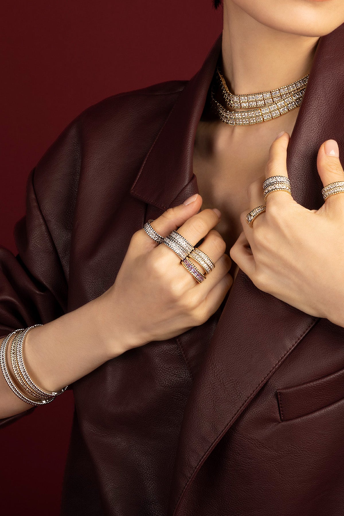 Woman wearing APM Monaco stacked jewelry set, bold sparkle meets burgundy leather elegance.