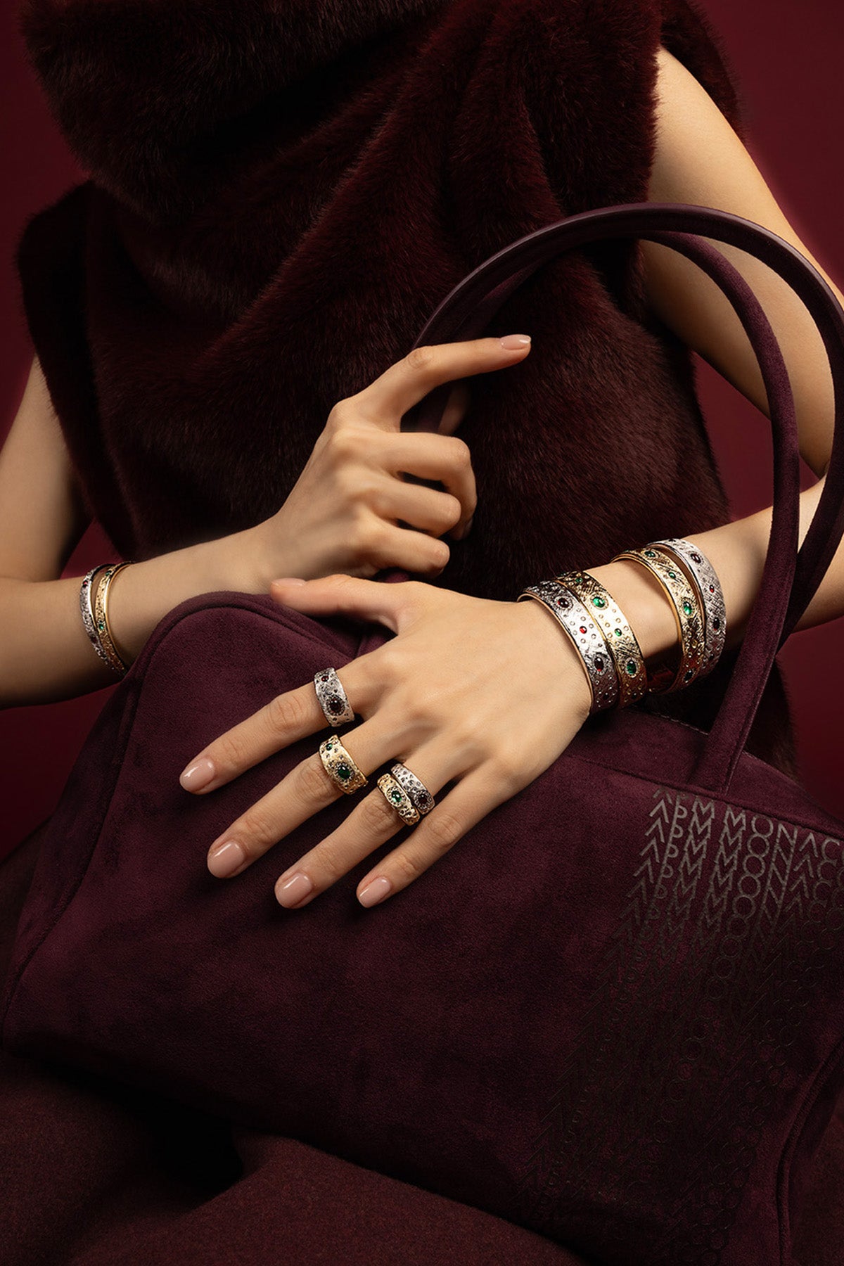 Woman wearing APM bangles and rings, a jeweled statement in rich burgundy elegance.