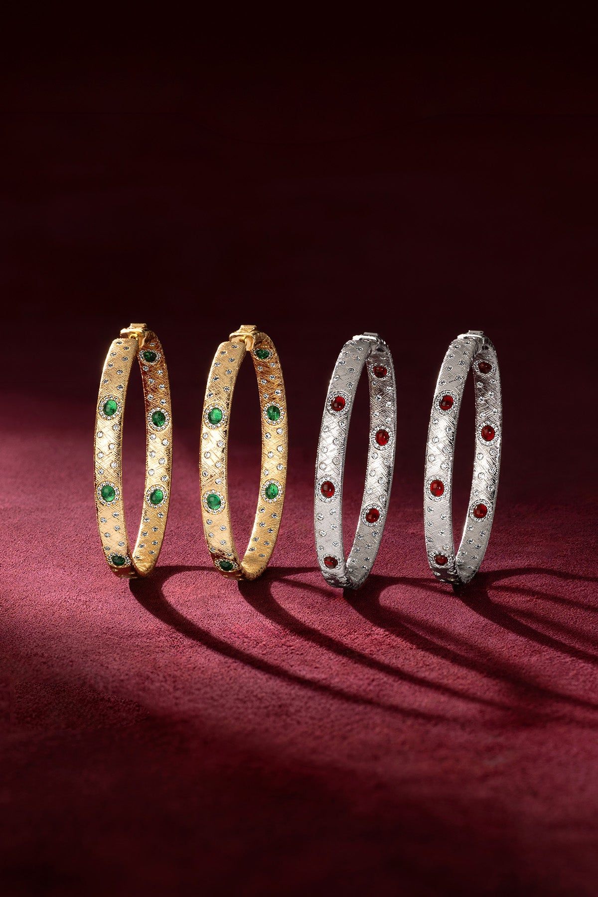 APM Bangles in gold and rhodium finish, sparkling with green and red hues.