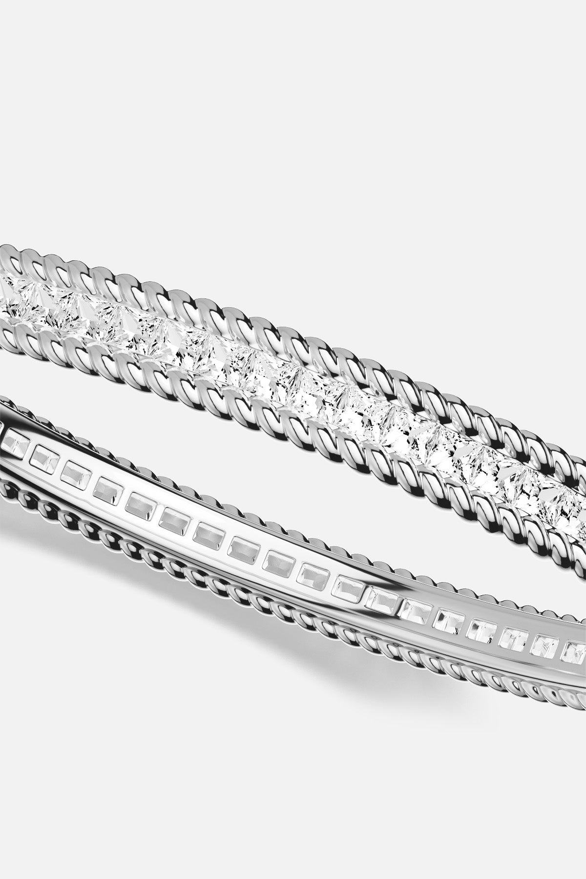 APM Bangle, twisted rhodium finish framing luminous stones, quiet modern elegance.