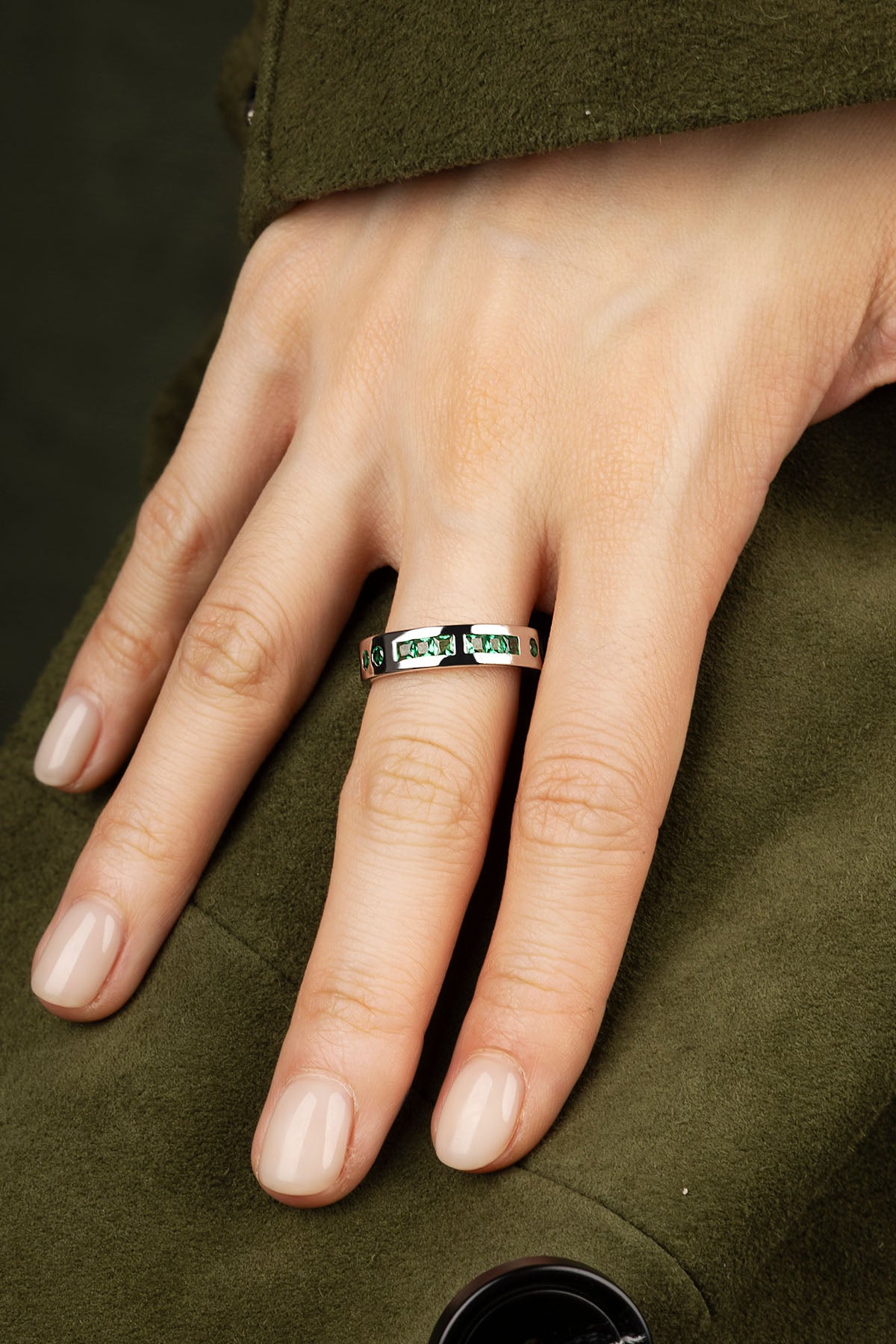Hand wearing a ring on a green fabric background