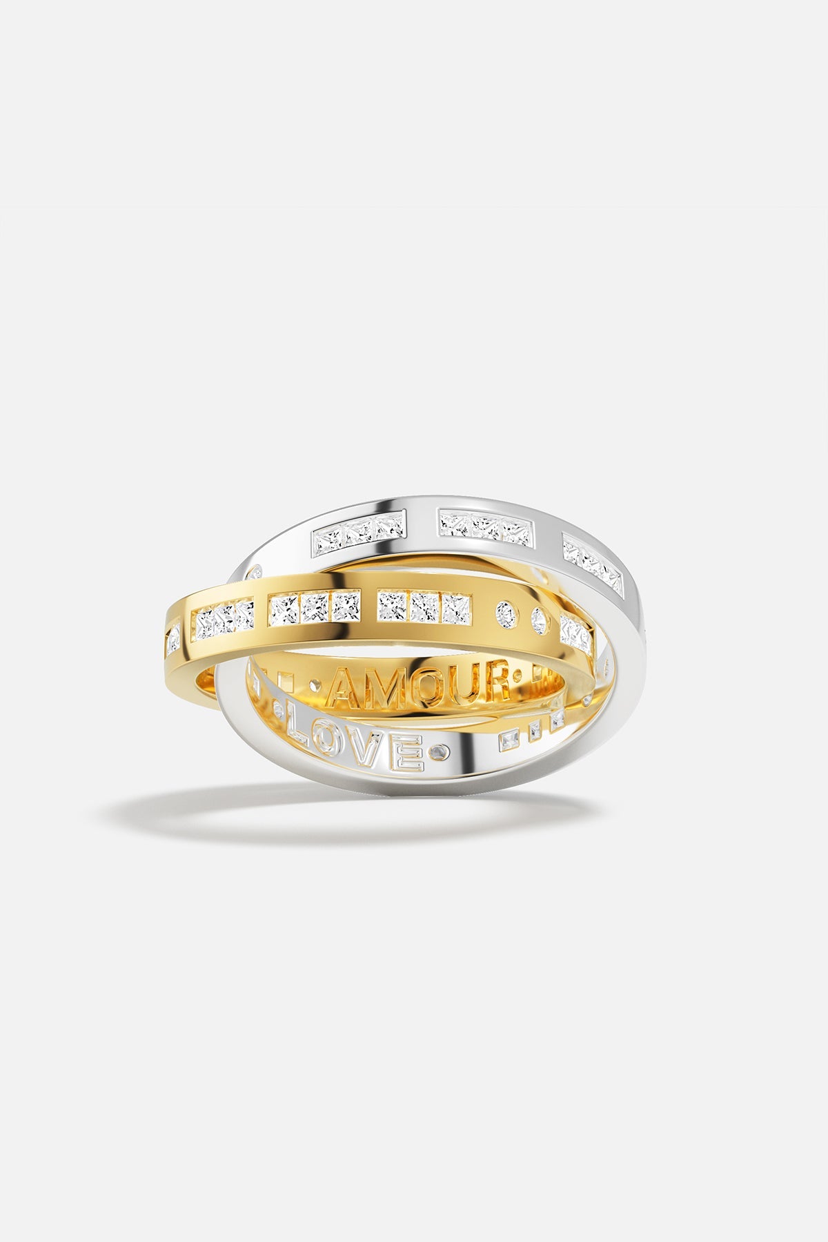 Rings APM Monaco: three interlocking rings—silver with pavé diamonds, yellow-gold with pavé diamonds, and a silver ring engraved AMOUR and LOVE.