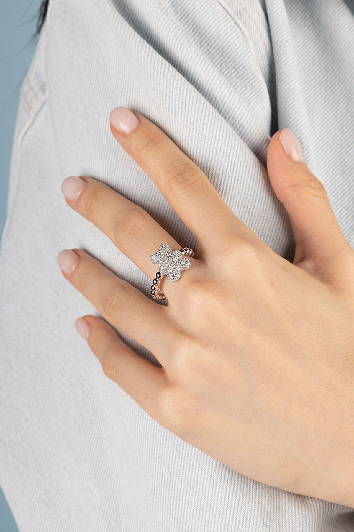 Hand wearing a silver ring with a cute bear