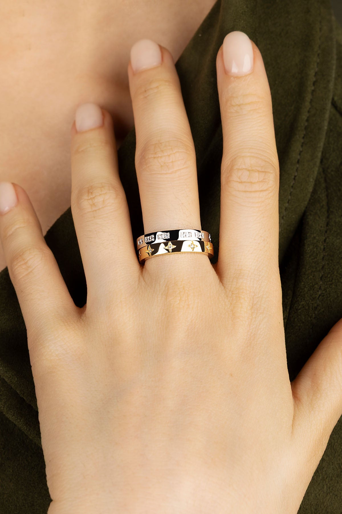 Close-up of a hand wearing a gold ring with engraved designs.