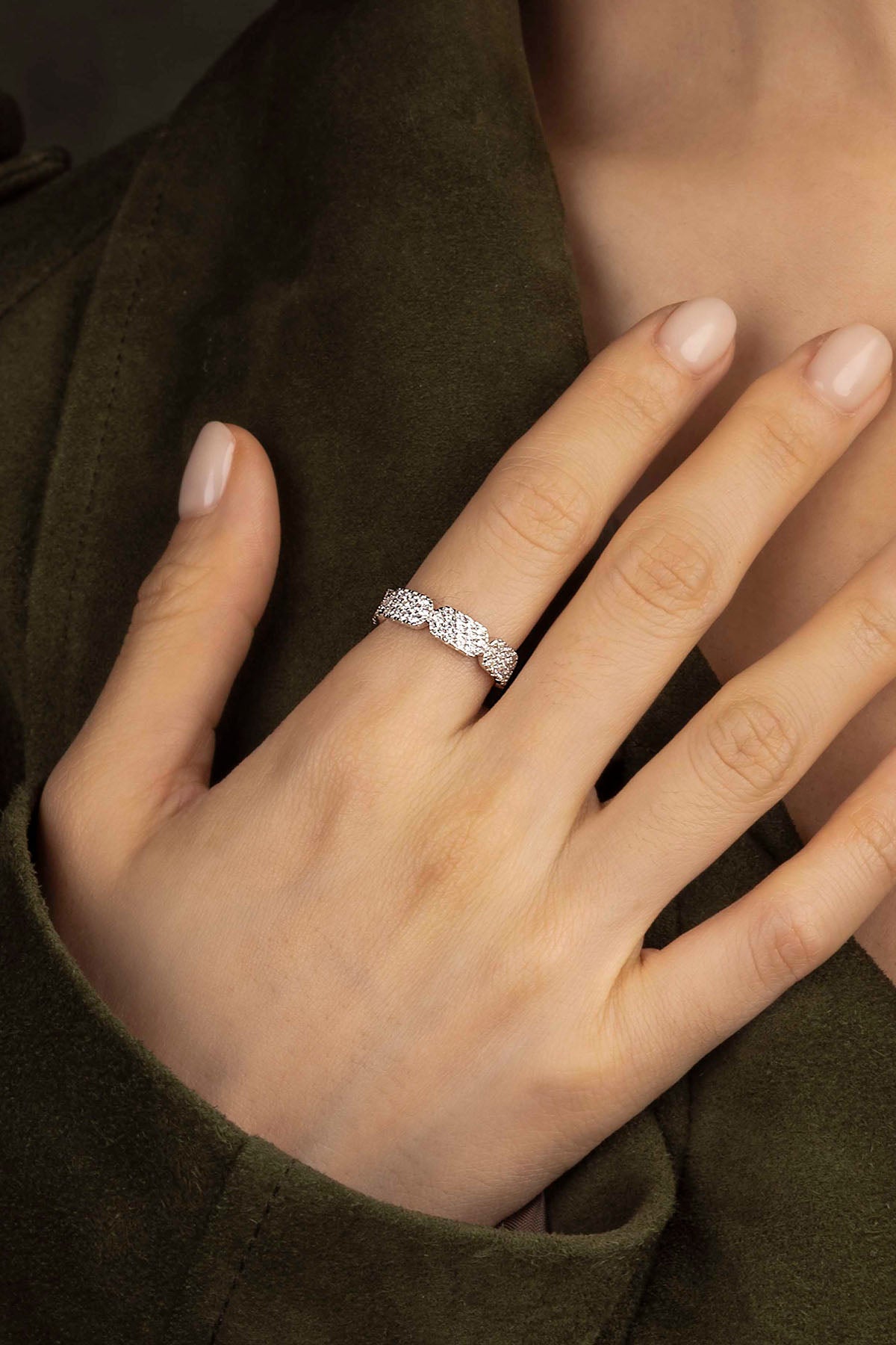 Close-up of a hand wearing a silver ring on a blurred background