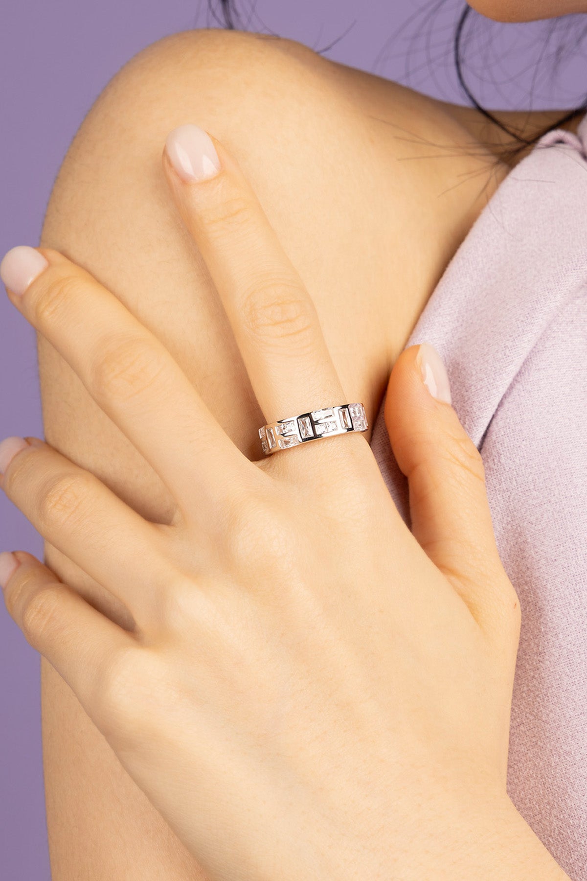 Hand wearing APM MONACO ice silver ring on a purple background