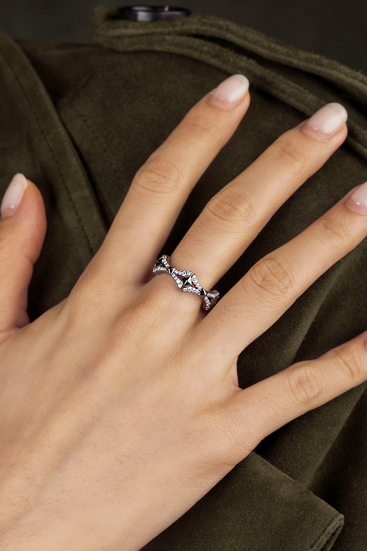Hand wearing a silver ring with a dark green coat