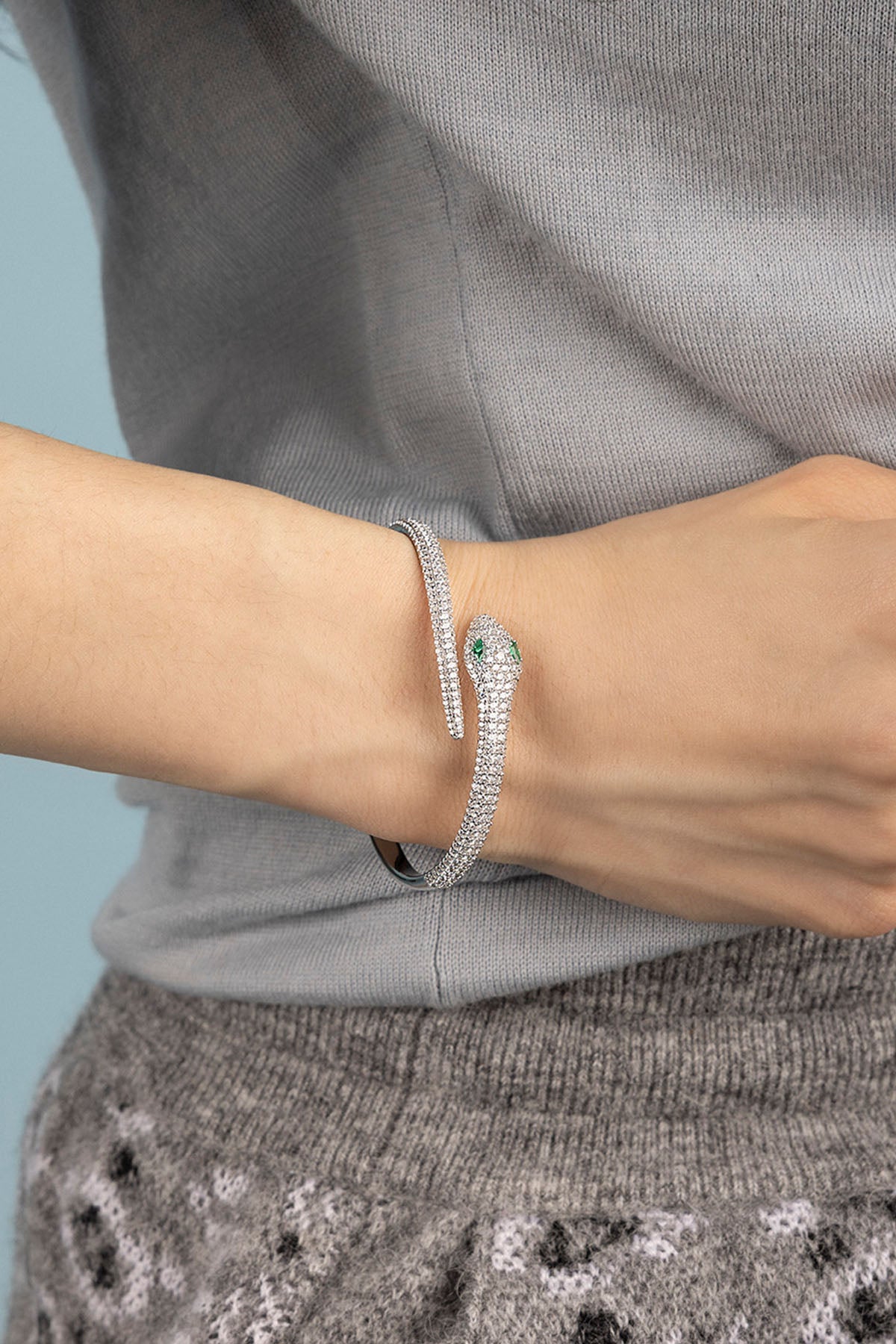 Silver bracelet on a person's wrist against a gray background