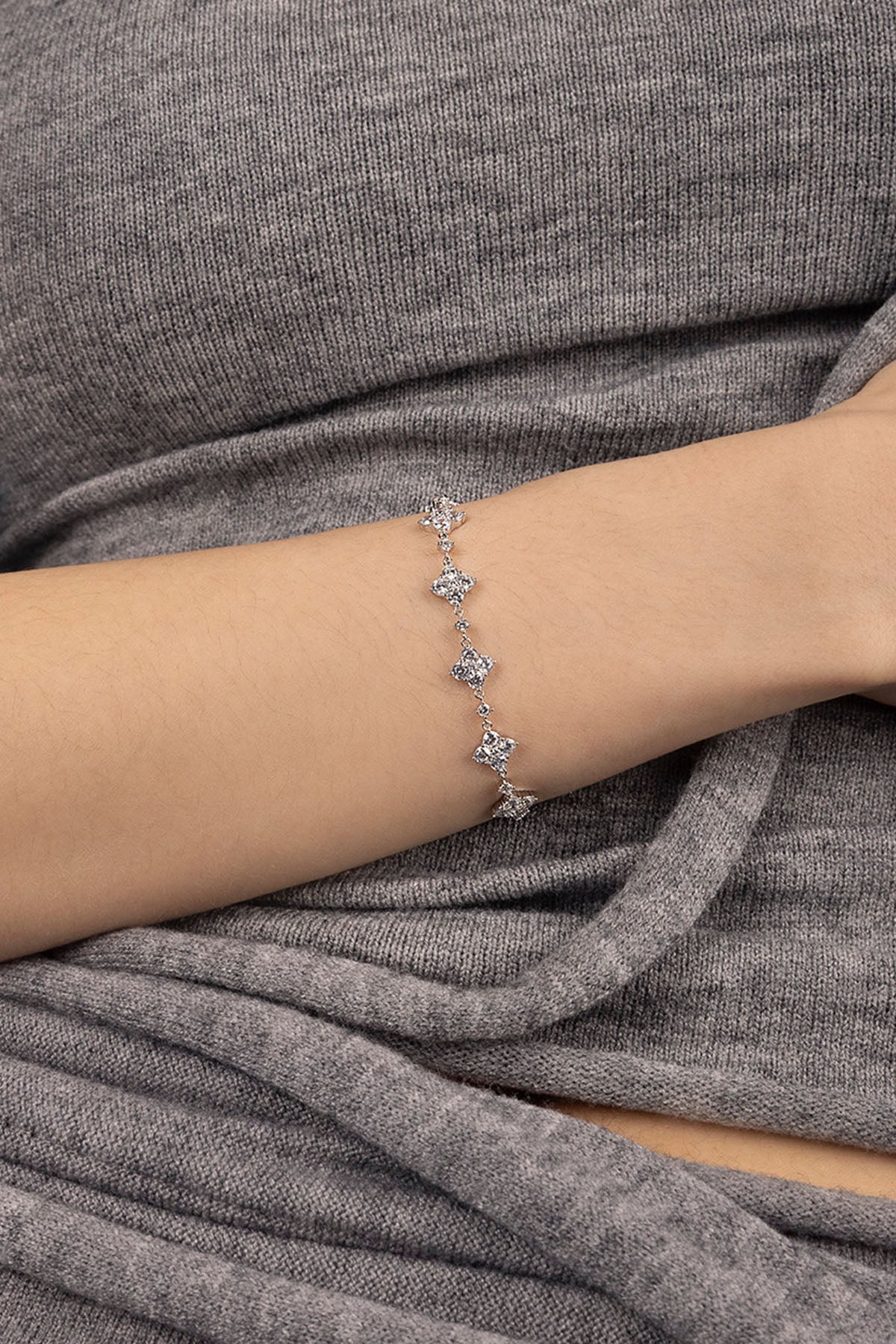 Silver bracelet on a wrist against a gray background