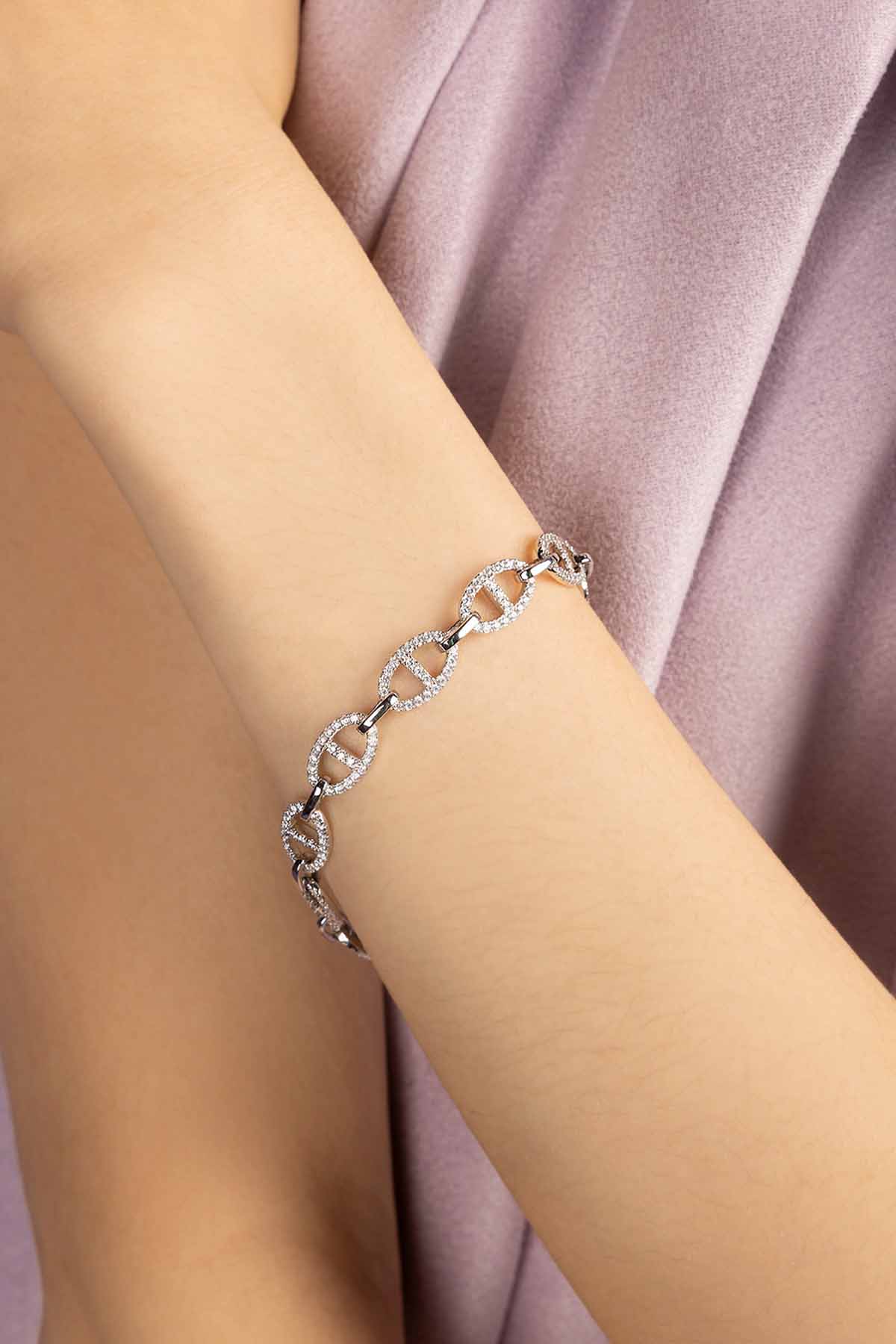 Silver bracelet on a person's wrist with a soft pink fabric background