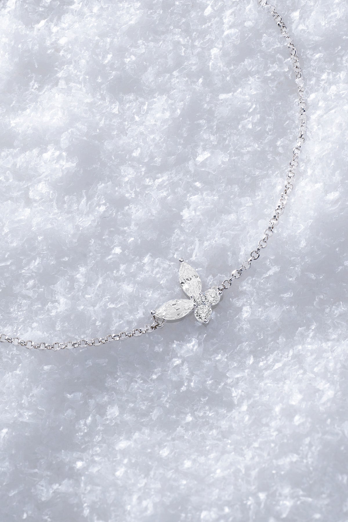 APM MONACO silver necklace with butterfly-shaped white pendant on a  snowy surface