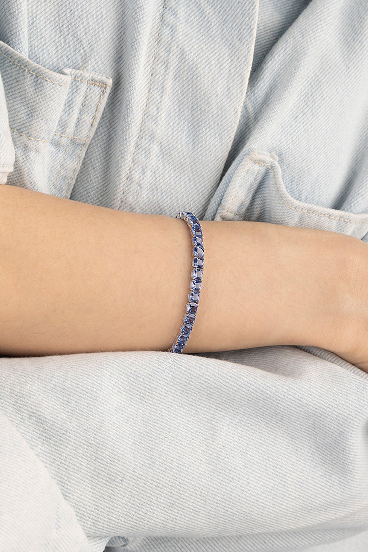 Person wearing a blue beaded bracelet on a light blue background