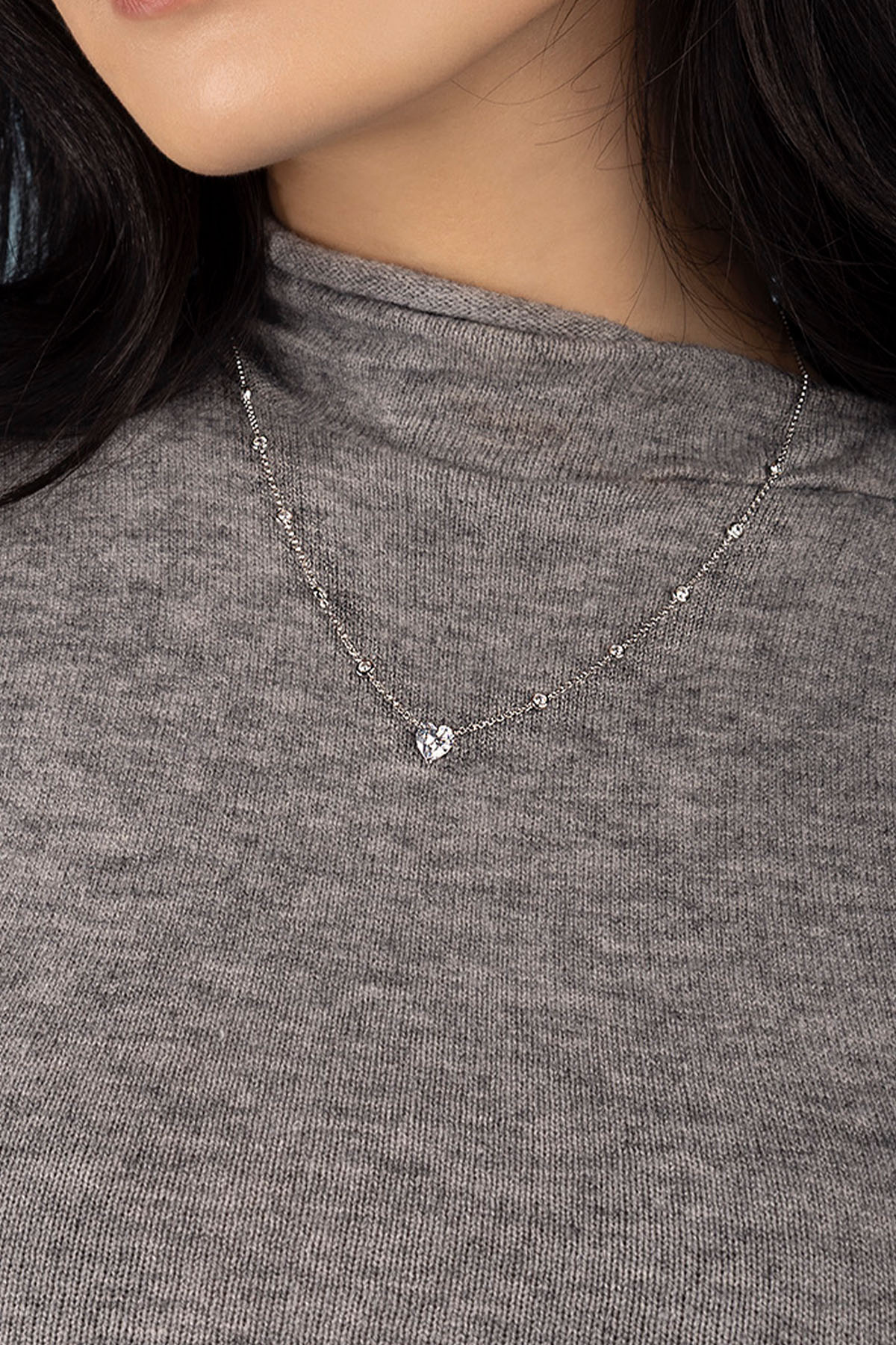 Necklace with a heart pendant worn by model in a gray shirt