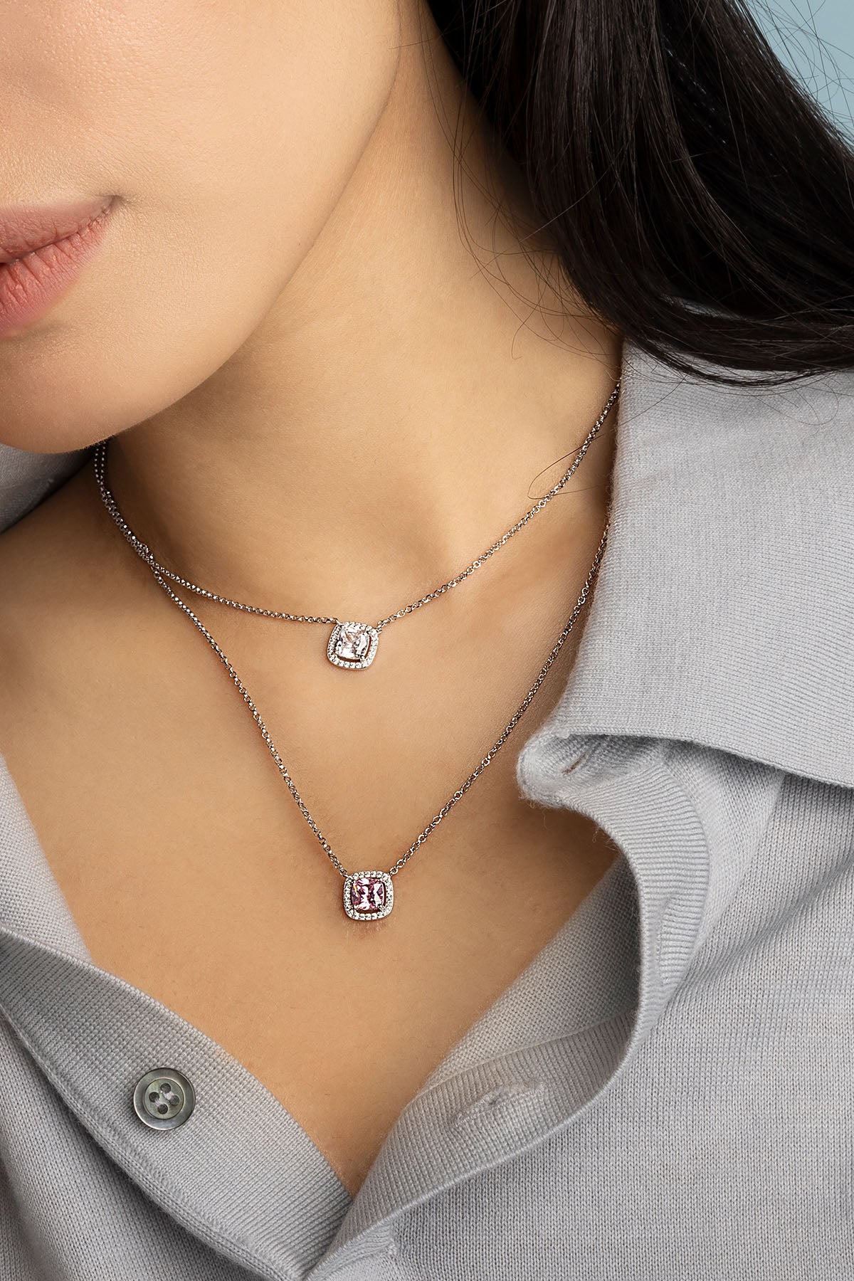 Close-up of a model wearing silver necklace with small square stone pendants.