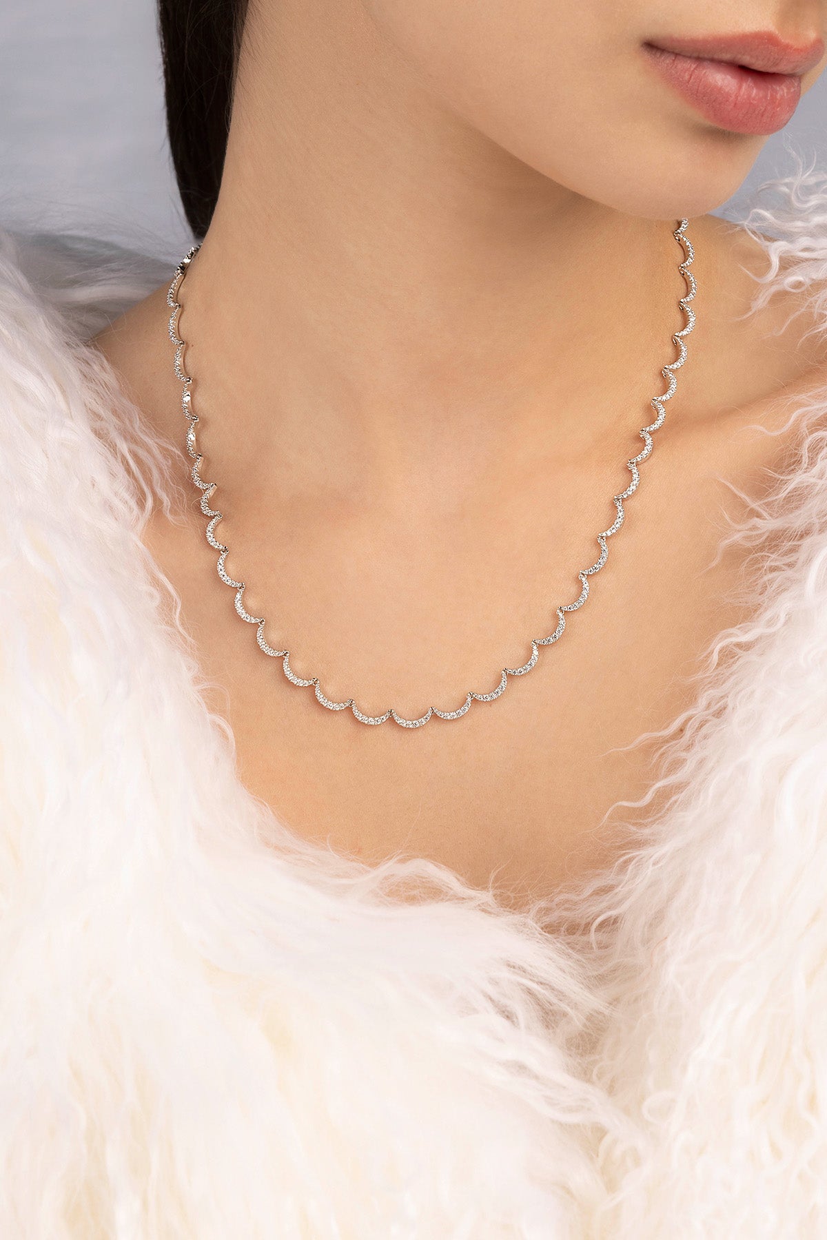Silver necklace worn by a person with a white feathered garment