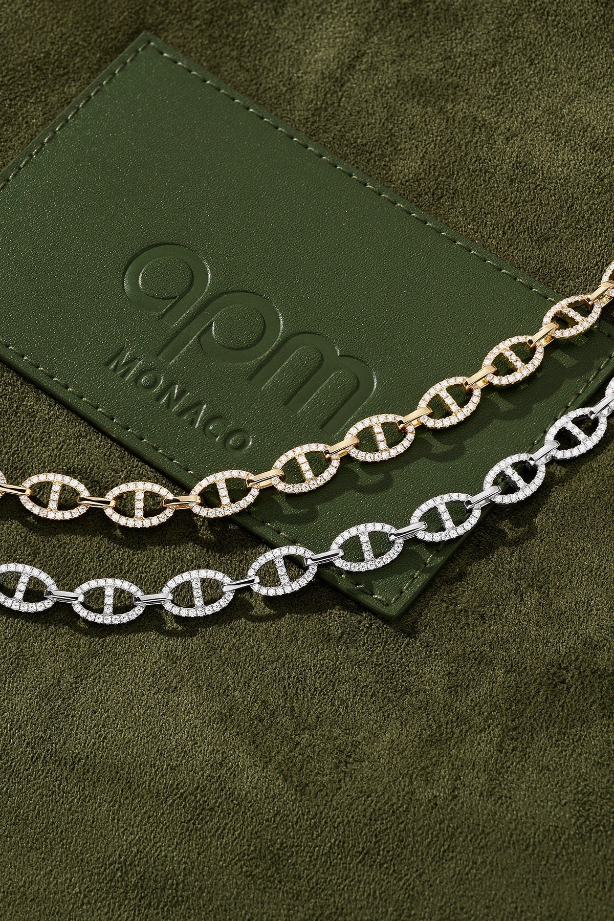 Two chain necklaces on a green card with 'apm monaco' branding.