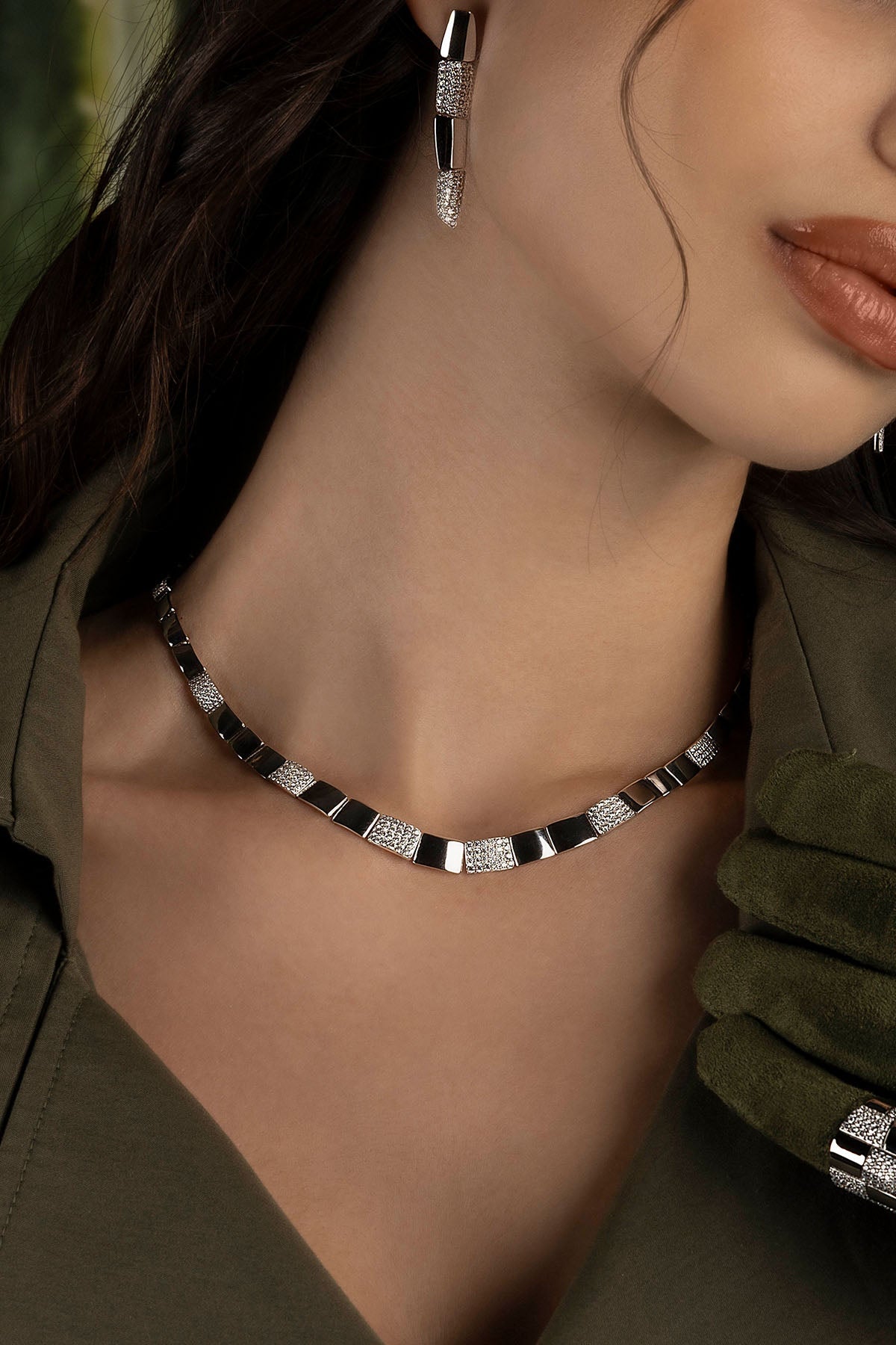Close-up of a model wearing a necklace and earrings with a blurred background