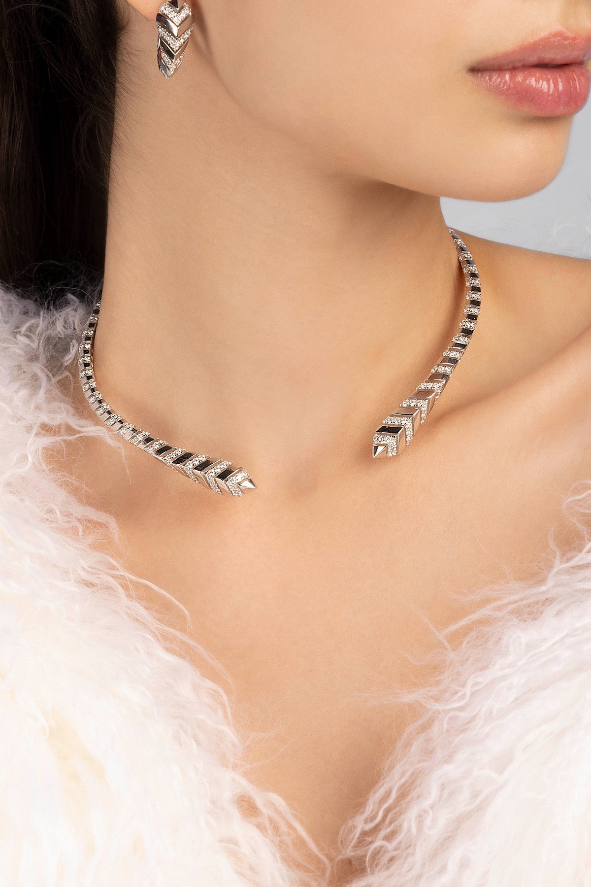 Necklace with matching earrings on a model wearing a white feathered garment.