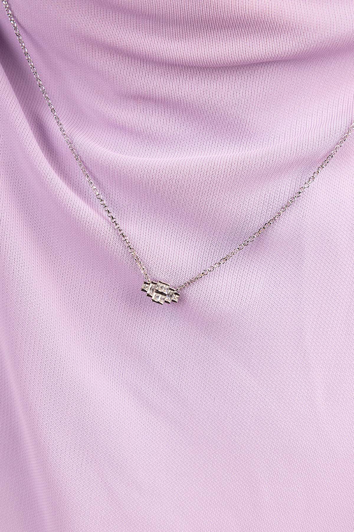 Silver necklace with a pendant on a pink fabric background
