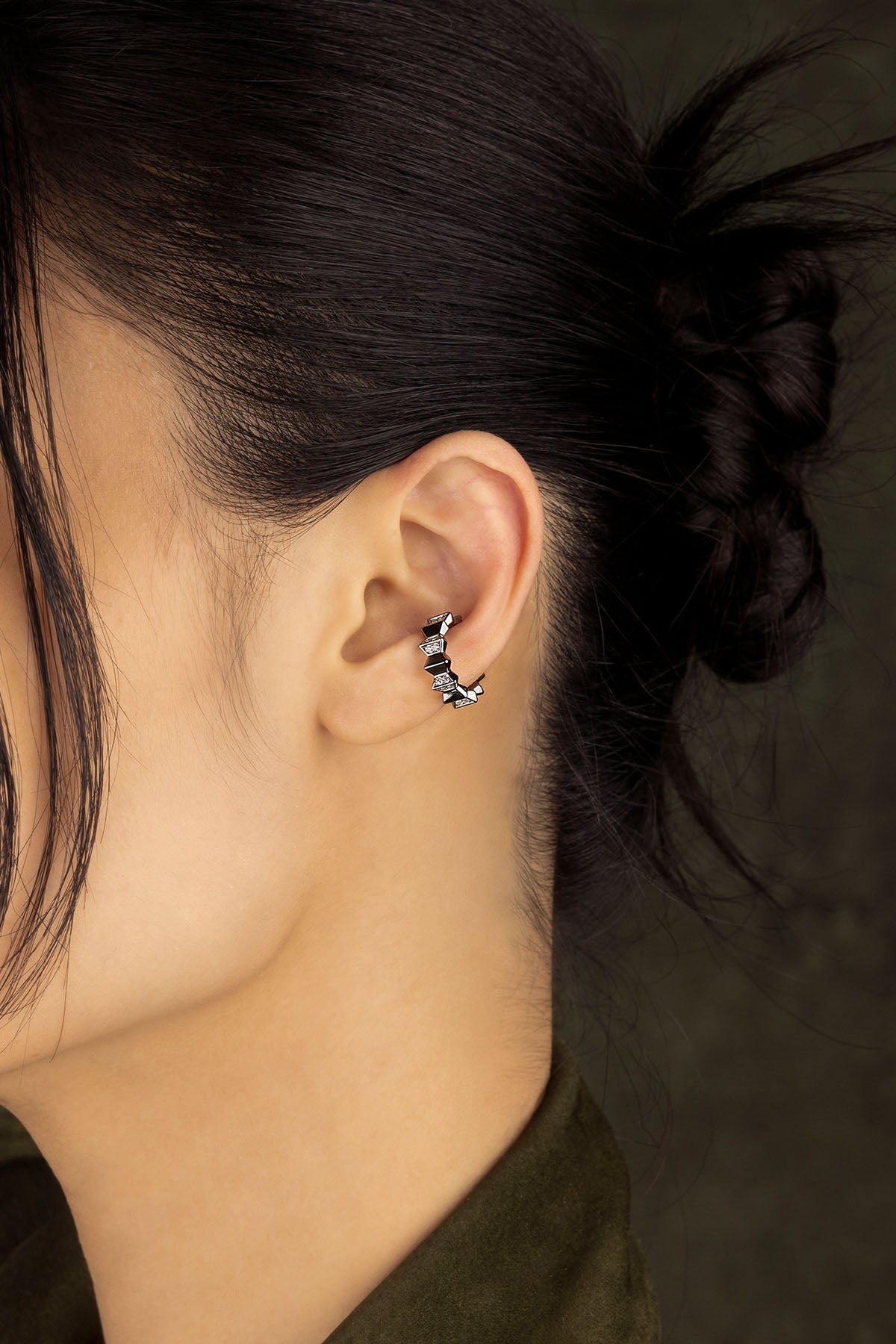 Close-up of an ear wearing a ear cuff with a dark background