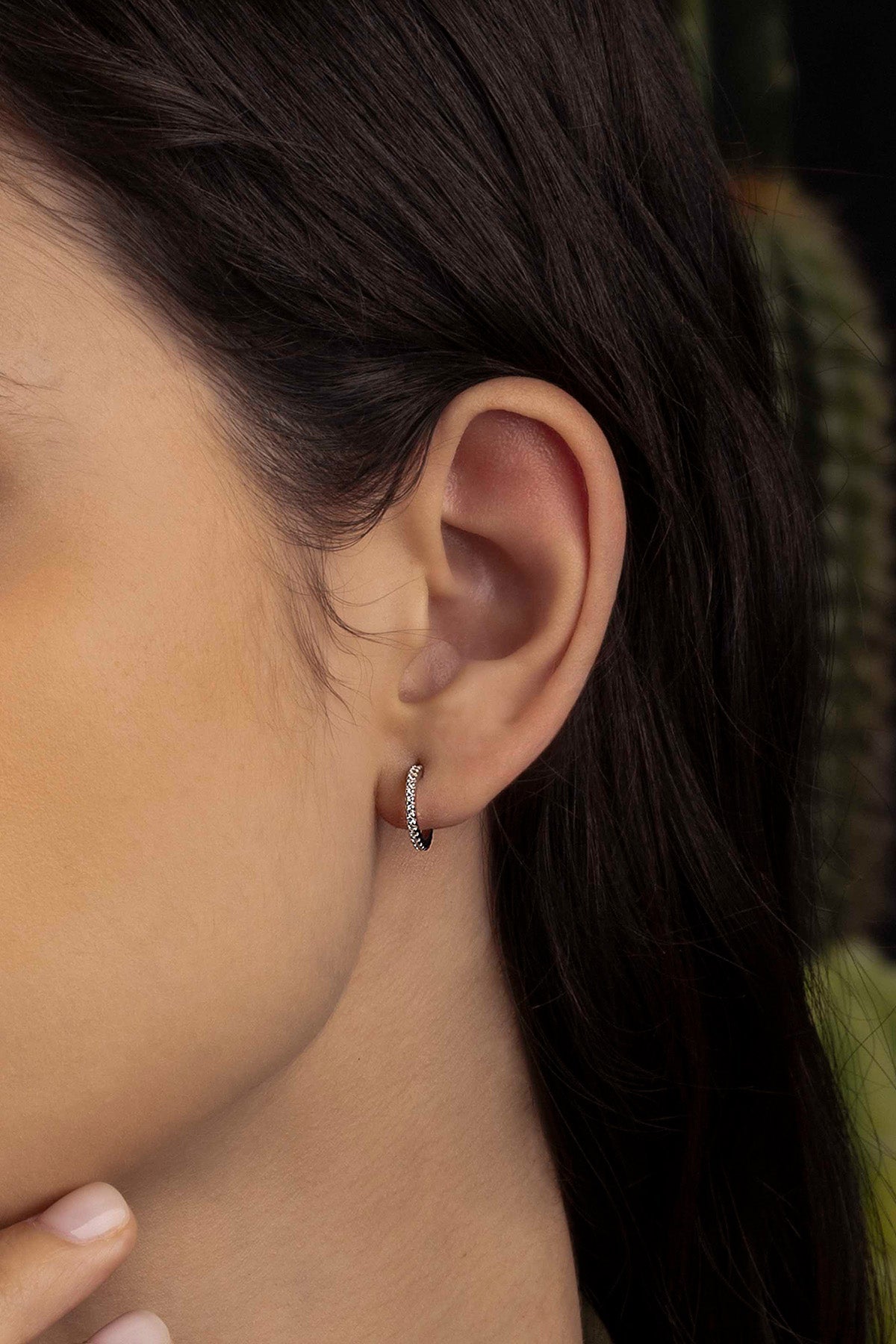 Close-up of an ear wearing a small hoop earring with blurred background