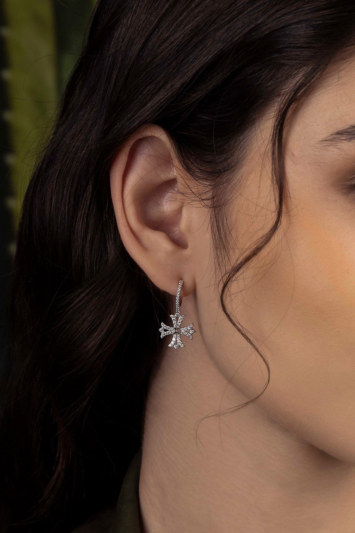 Close-up of a person wearing a silver earring with a blurred background