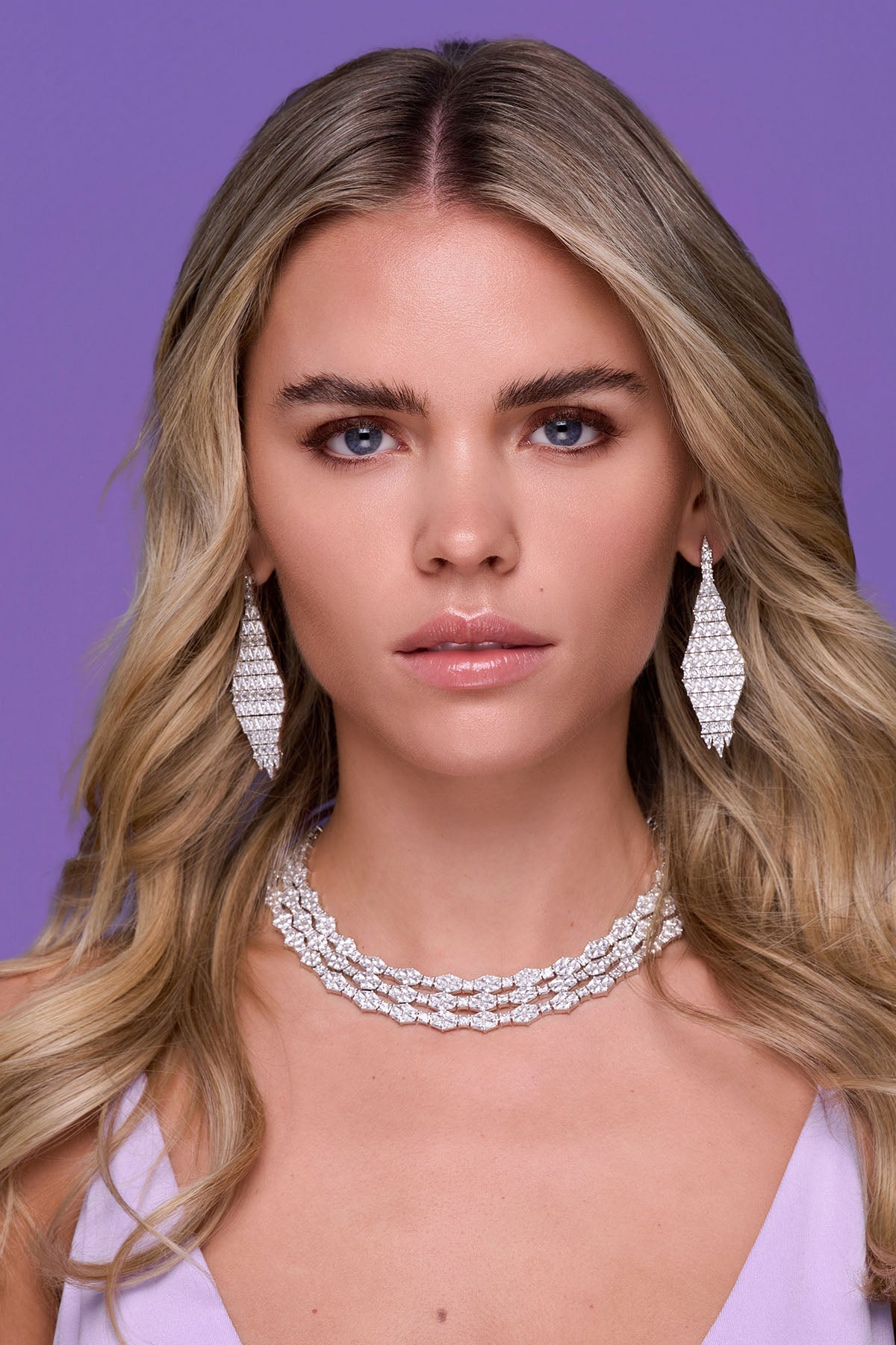 a person wearing zirconia earrings with a purple background