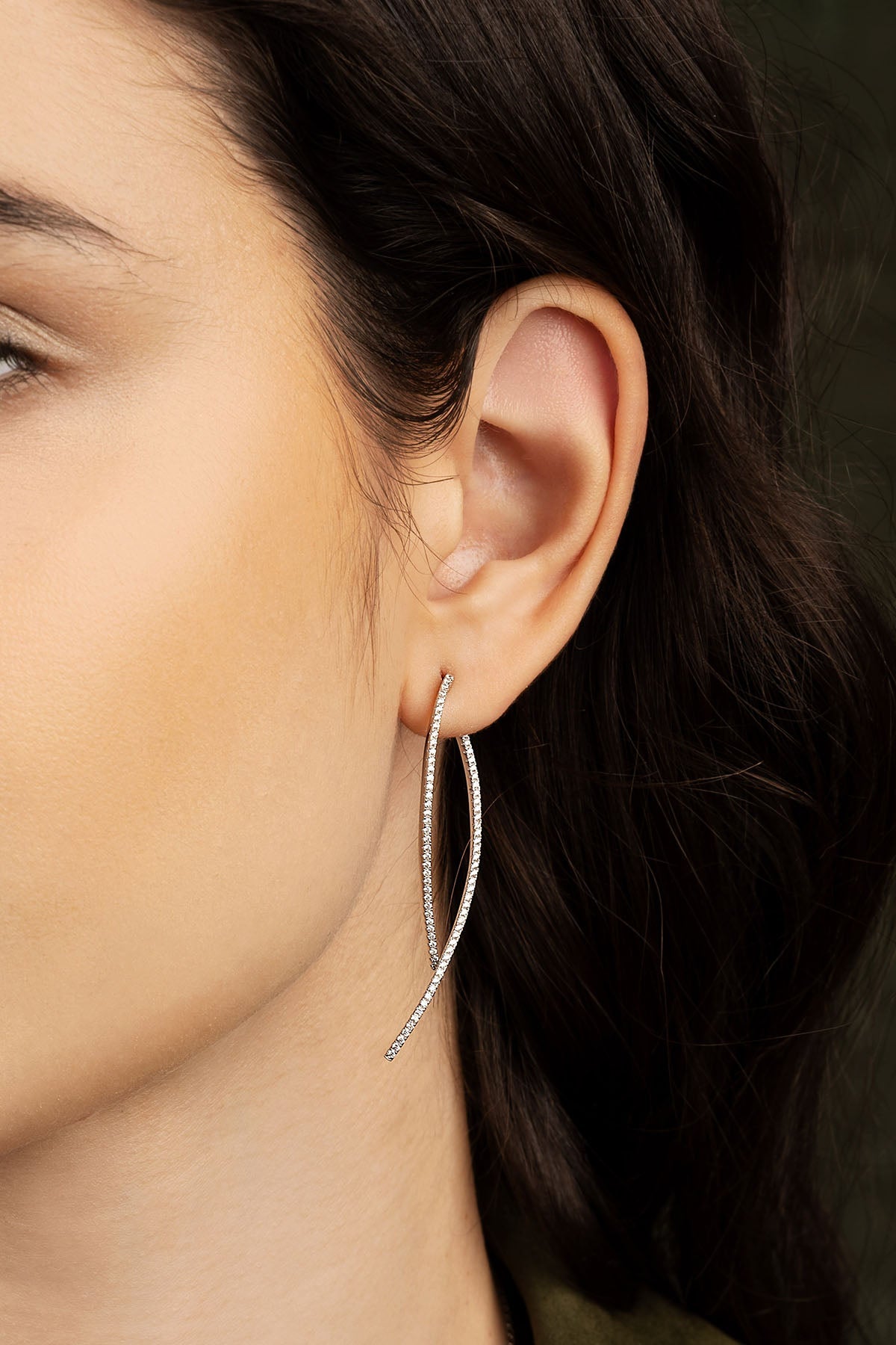 Close-up of a person wearing a silver earring with a blurred background