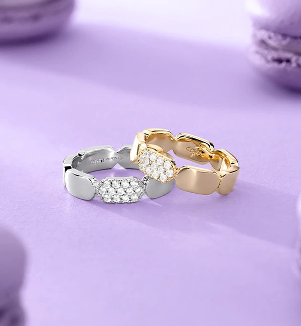 two APM MONACO yellow gold and silver rings on a light purple background