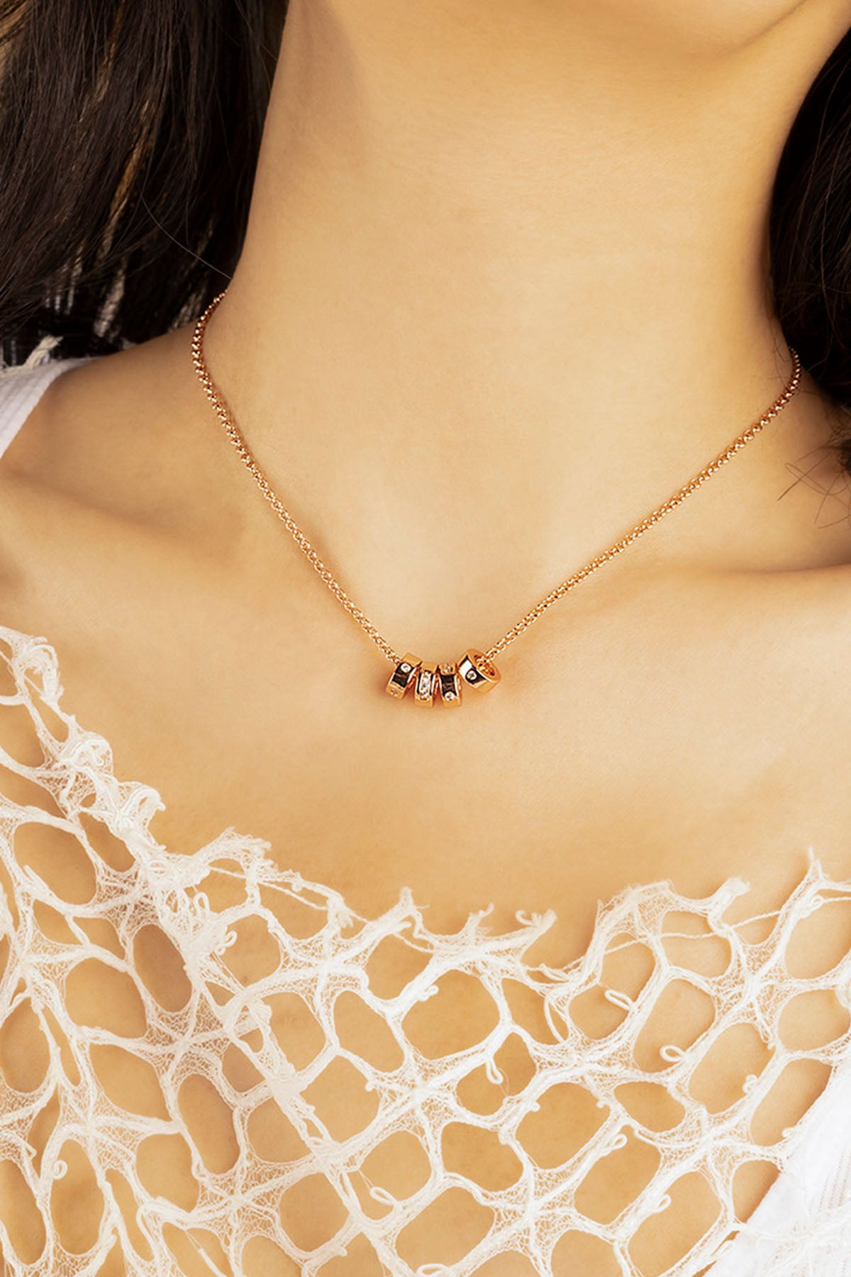 Necklace with small stones worn by a person on a lace garment