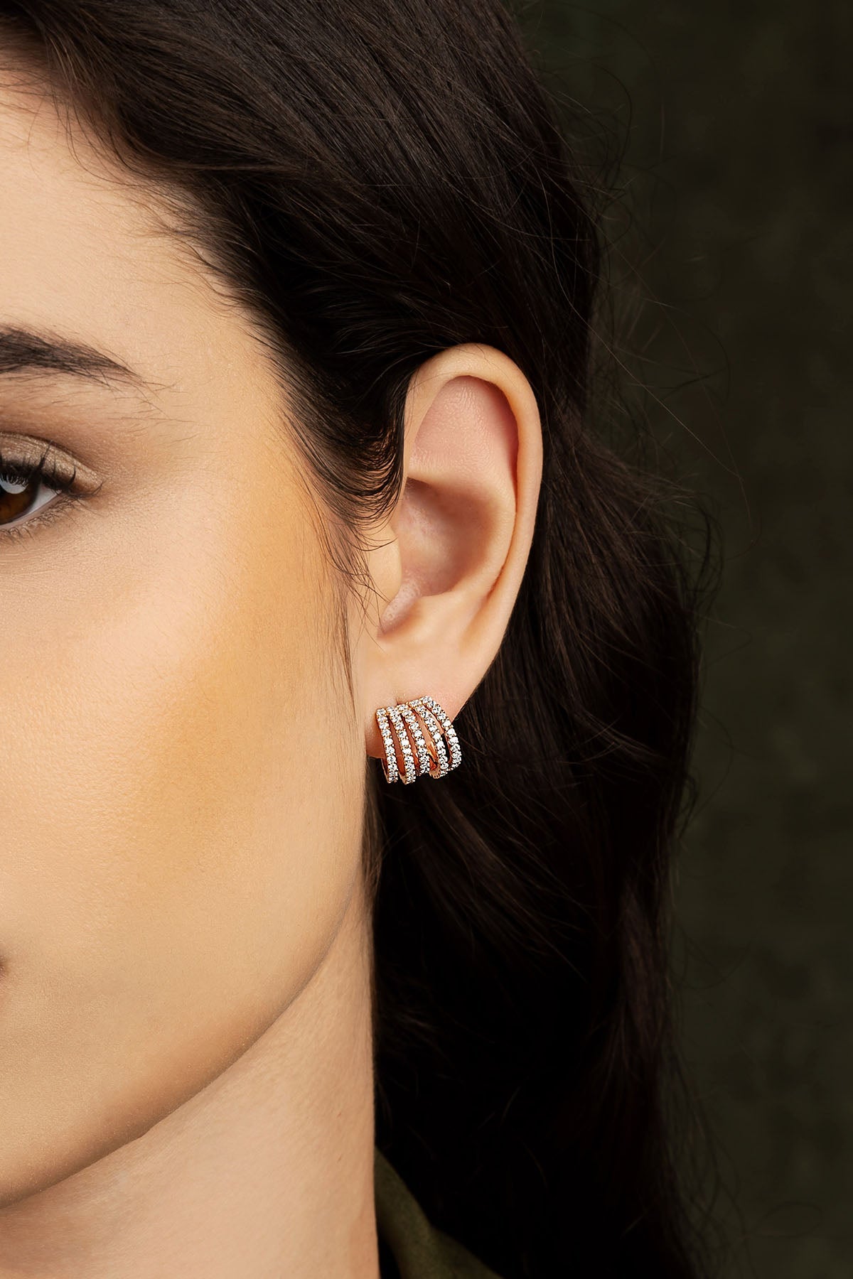 Close-up of a woman's ear wearing a silver earring on a dark background