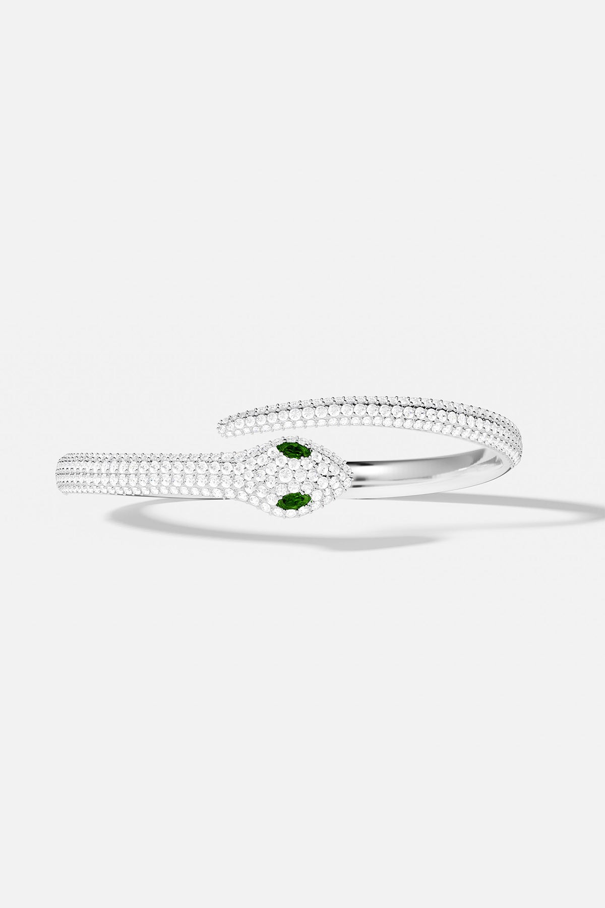 Silver bangle with green gemstones on a white background