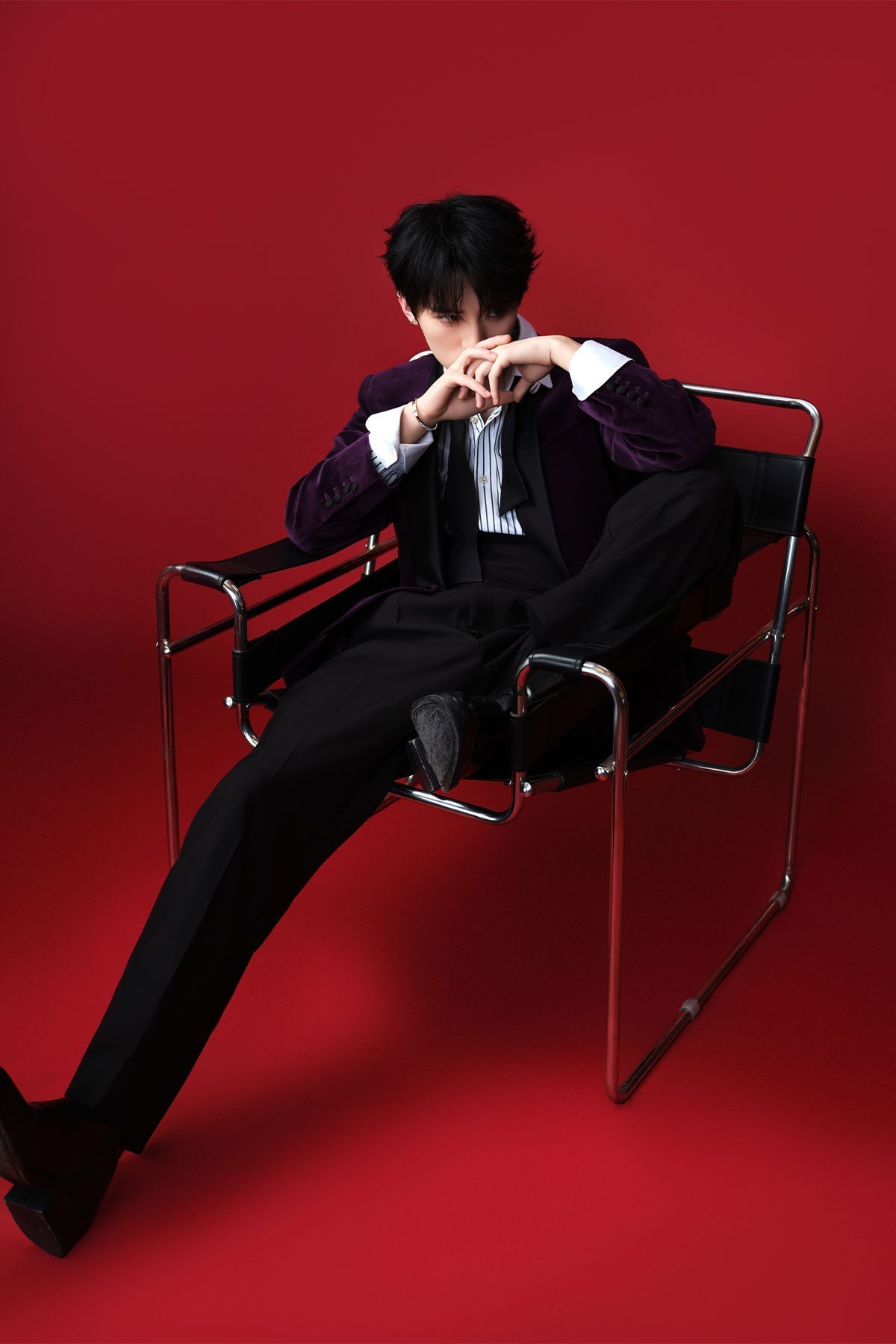 Model sitting on a chair against a red background