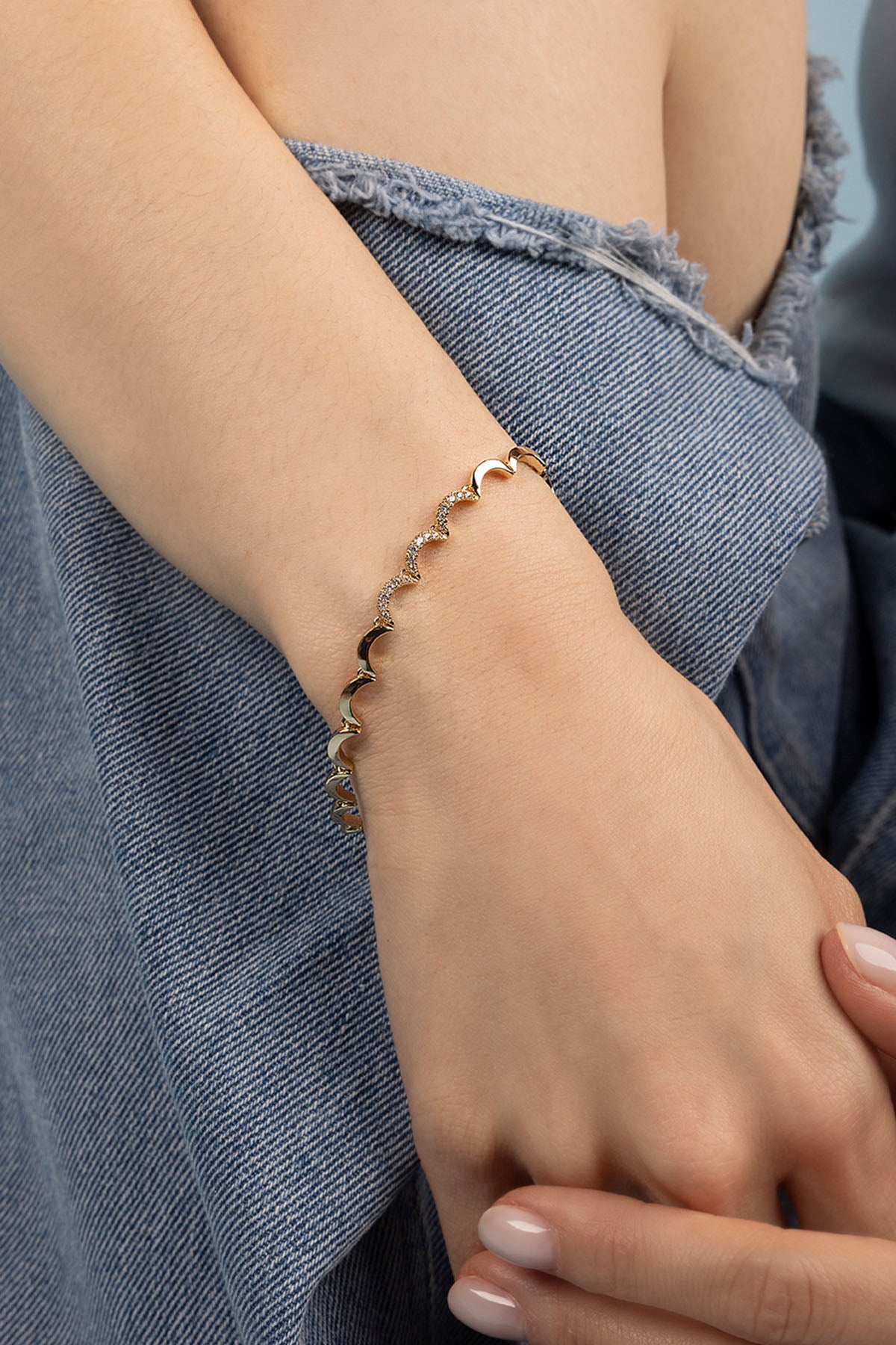 Close-up of a hand wearing a bracelet with a denim background