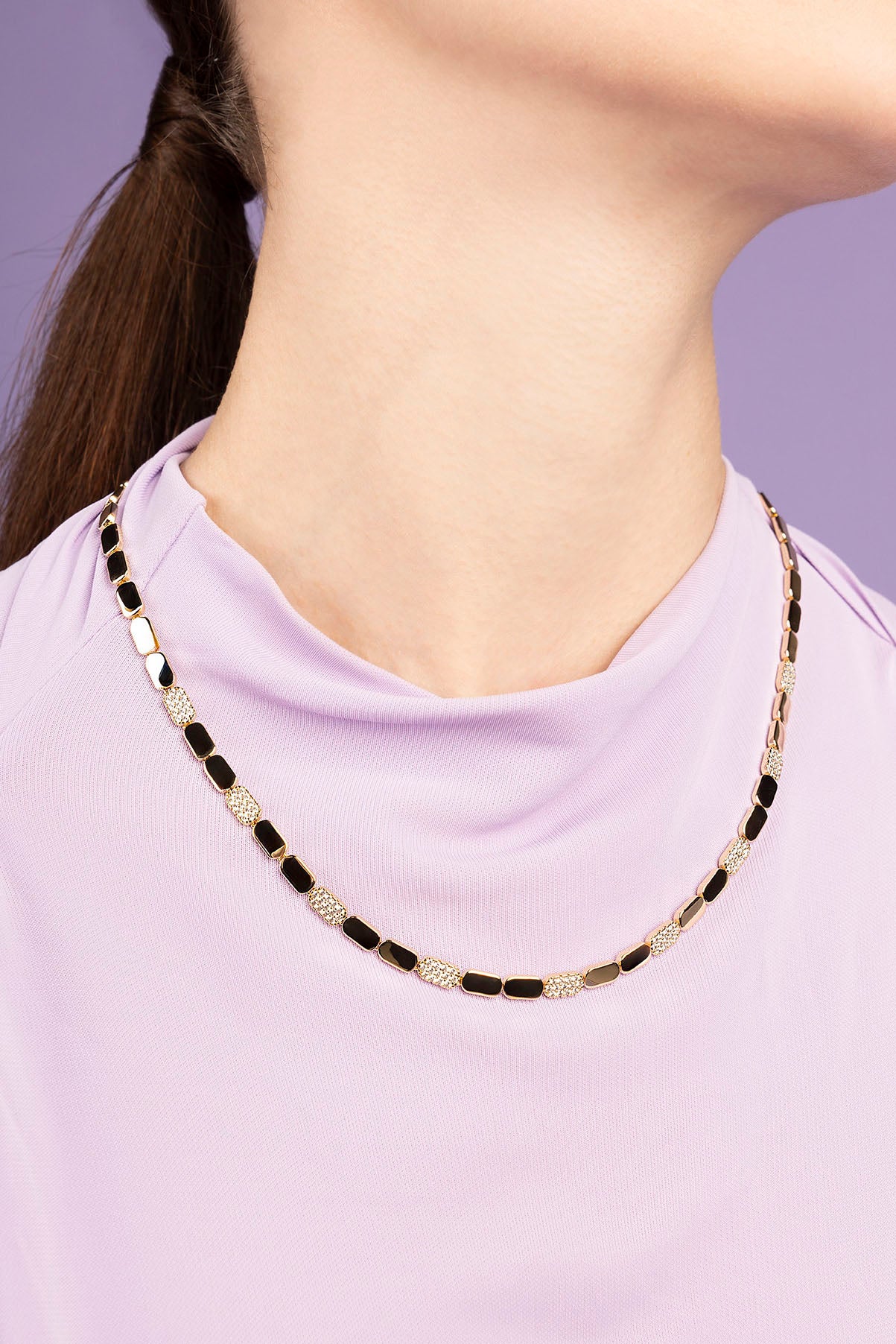 APM MONACO DAINTY gold adjustable necklace worn by a person against a purple background