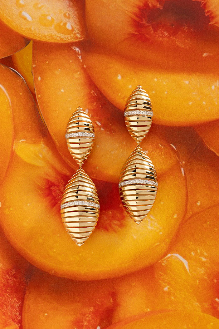 APM Monaco Statement Rayon de Soleil Earrings in Yellow Gold on juicy peach jam background